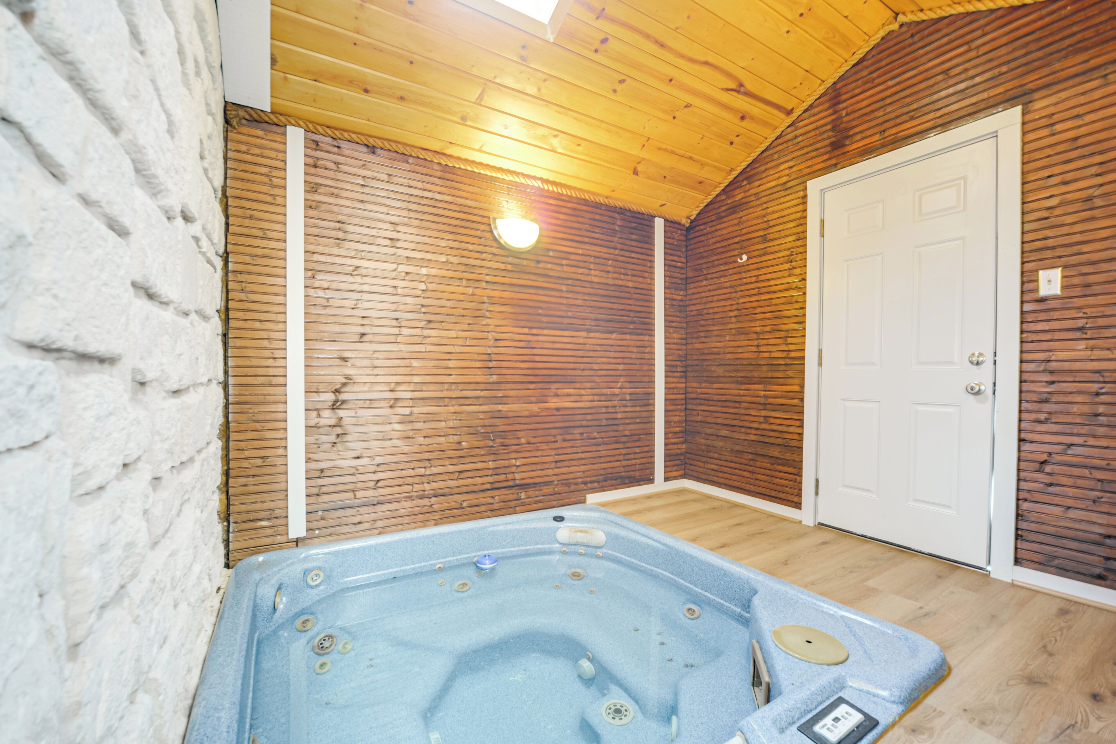 Ein Zimmer mit Holzboden, einer weißen Tür und einer Whirlwanne.