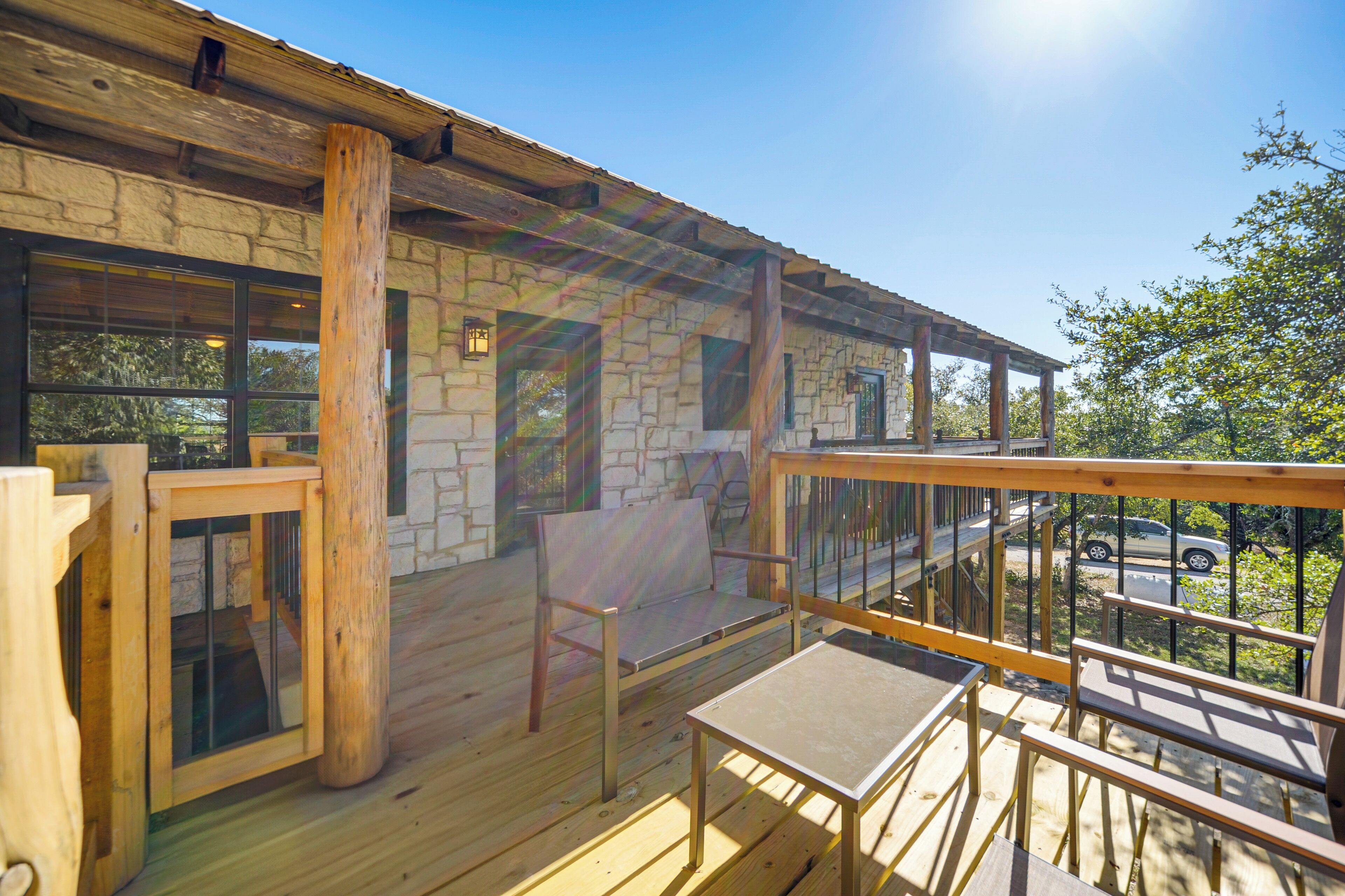 A wooden deck with a stone wall, a wooden chair, and a table.