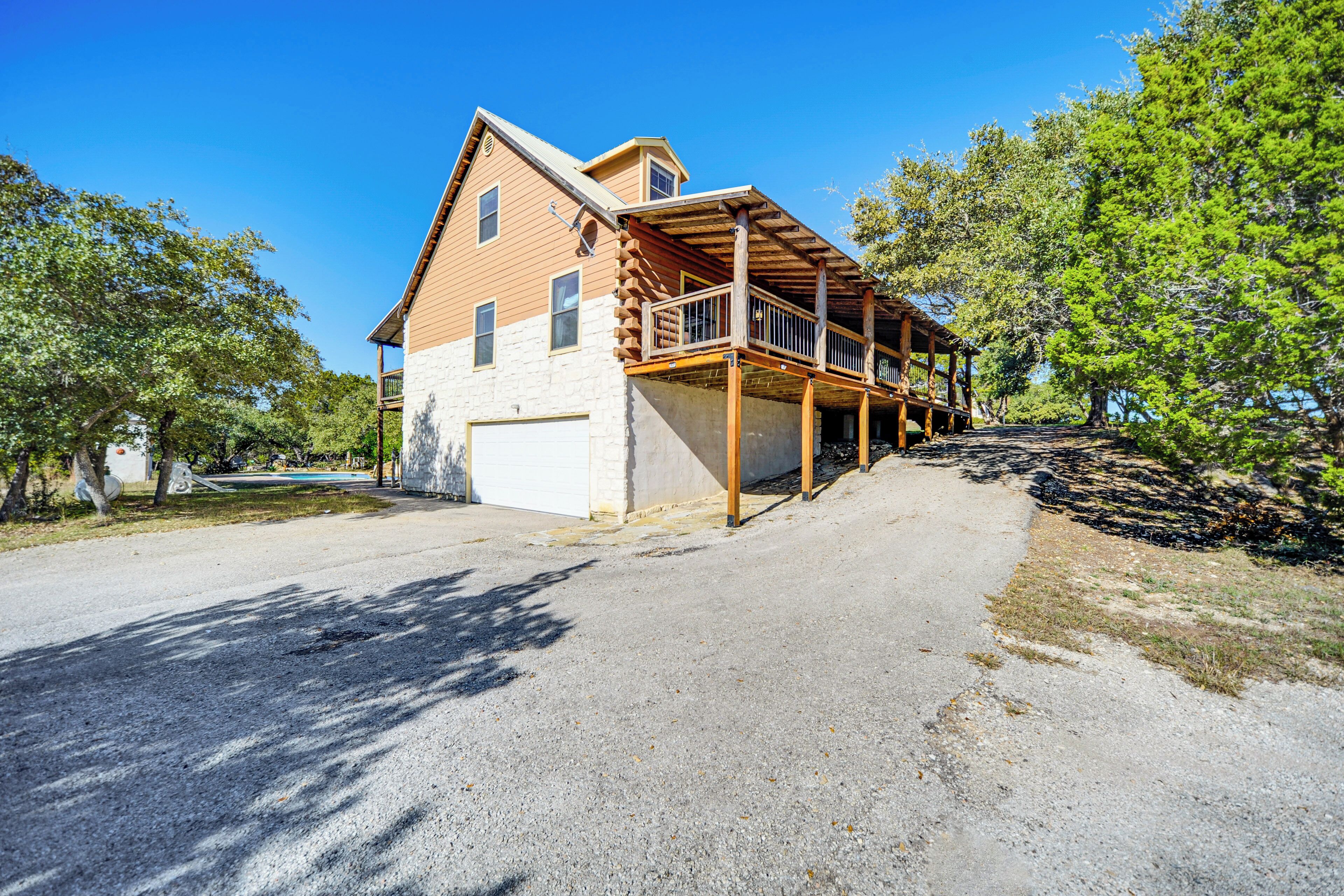 A two-story wooden house with a balcony, a garage, and a driveway.