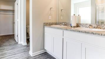 A bathroom with two sinks, a large mirror, and a walk-in closet.