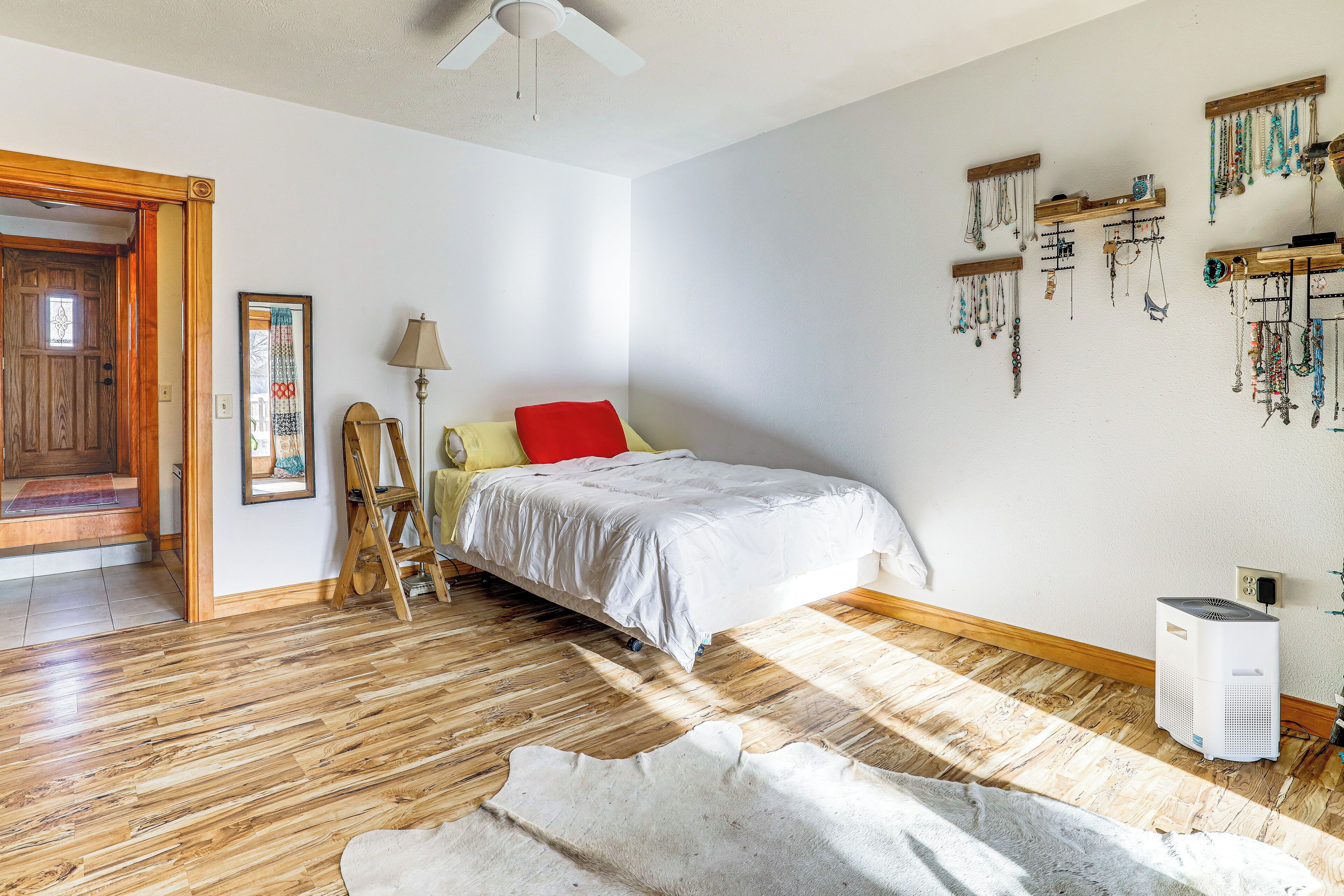 A bedroom with a bed, wooden flooring, a heater, and wall-mounted jewelry.