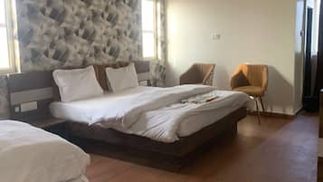 A hotel room with a large bed, a chair, a ceiling fan, and a patterned wall.
