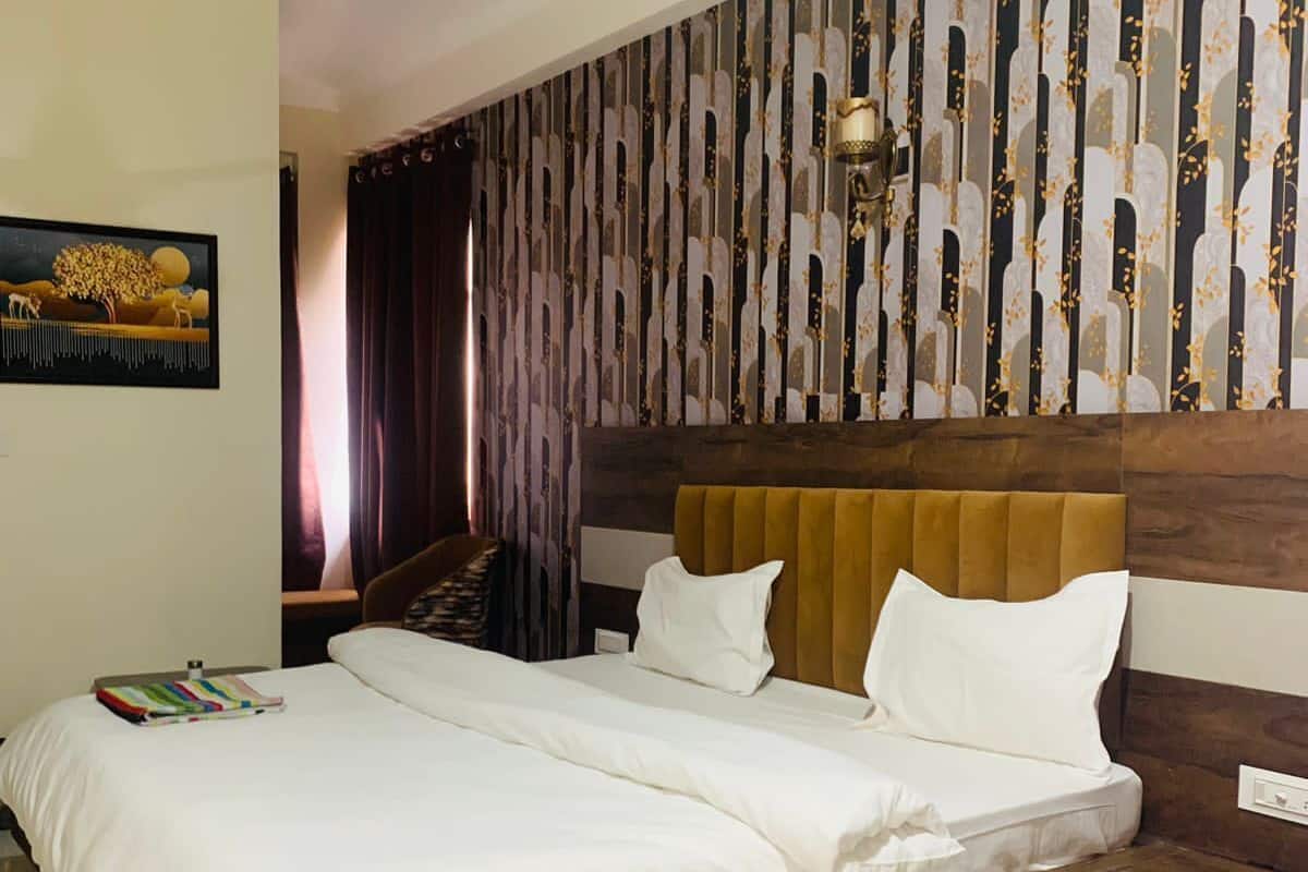 A bedroom with a wooden headboard, a large bed with white linens, a ceiling fan, and a patterned wall.