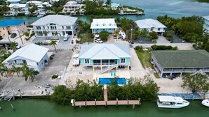 A coastal property with a swimming pool, docked boats, and multiple buildings. - Coco4Fun New Luxury Canal Front with Pool/Spa/Dock (Marathon)