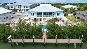 A coastal house with a swimming pool, dock, and surrounding greenery. - Coco4Fun New Luxury Canal Front with Pool/Spa/Dock (Marathon)