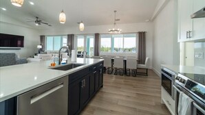 A modern kitchen with a large island, built-in appliances, and pendant lighting. - Coco4Fun New Luxury Canal Front with Pool/Spa/Dock (Marathon)