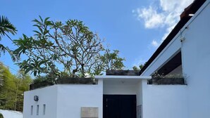 A white building with a black door, a sign reading "Villa Bettino 2", and a paved entrance area. - Villa Casa Petite 2 (Bali)