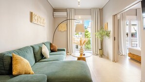 A modern living room with a sofa, a lamp, and a potted plant. - Acropolis Path - Elegant Apartment near Plaka (Athina)