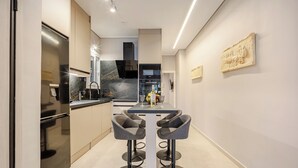 A modern kitchen with a central island, bar stools, and a dining table. - Acropolis Path - Elegant Apartment near Plaka (Athina)
