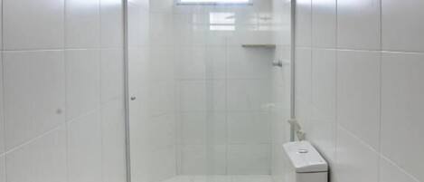 Ein modernes Badezimmer mit Duschkabine aus Glas, Toilette und einer Toilettenpapierrolle auf dem Boden.