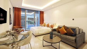 Ein modernes Hotelzimmer mit einem Glastisch, einer Couch, einem Bett und einem großen Fenster mit Vorhängen.