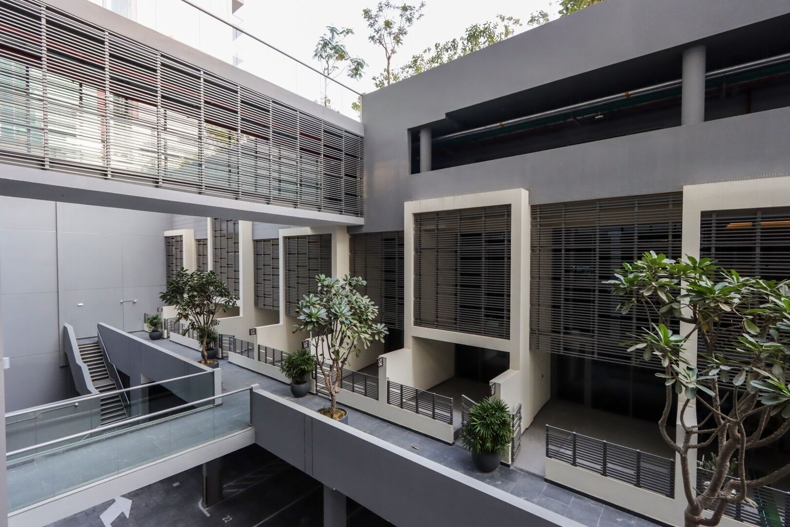 Un bâtiment moderne à plusieurs étages, doté de grandes fenêtres et agrémenté de plantes d’intérieur.