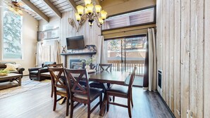A cozy living room with a fireplace, wooden furniture, and a TV mounted on the wall. - Modern Cabin for 8, Near Slopes + Canyon Lodge! (Mammoth Lakes)