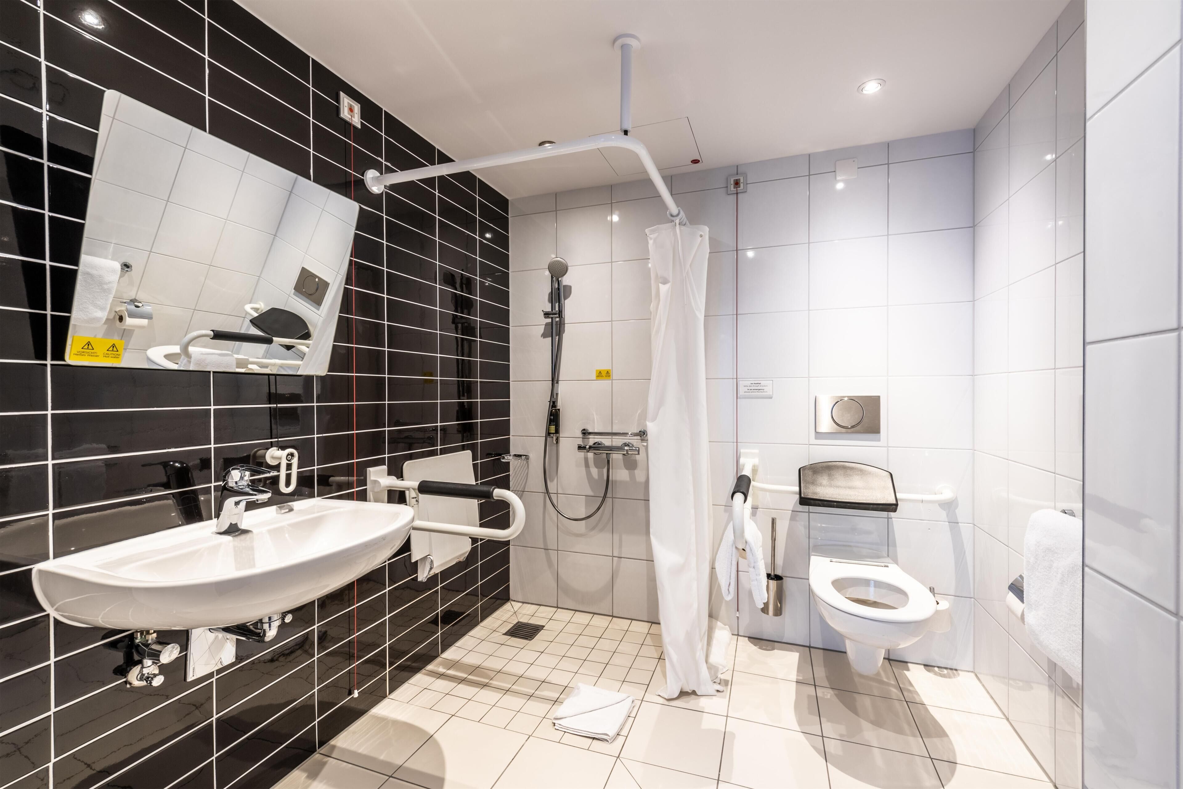 Un baño moderno con lavamanos, inodoro y ducha blancos.