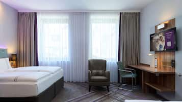A hotel room with a bed, a chair, a TV, and a desk.