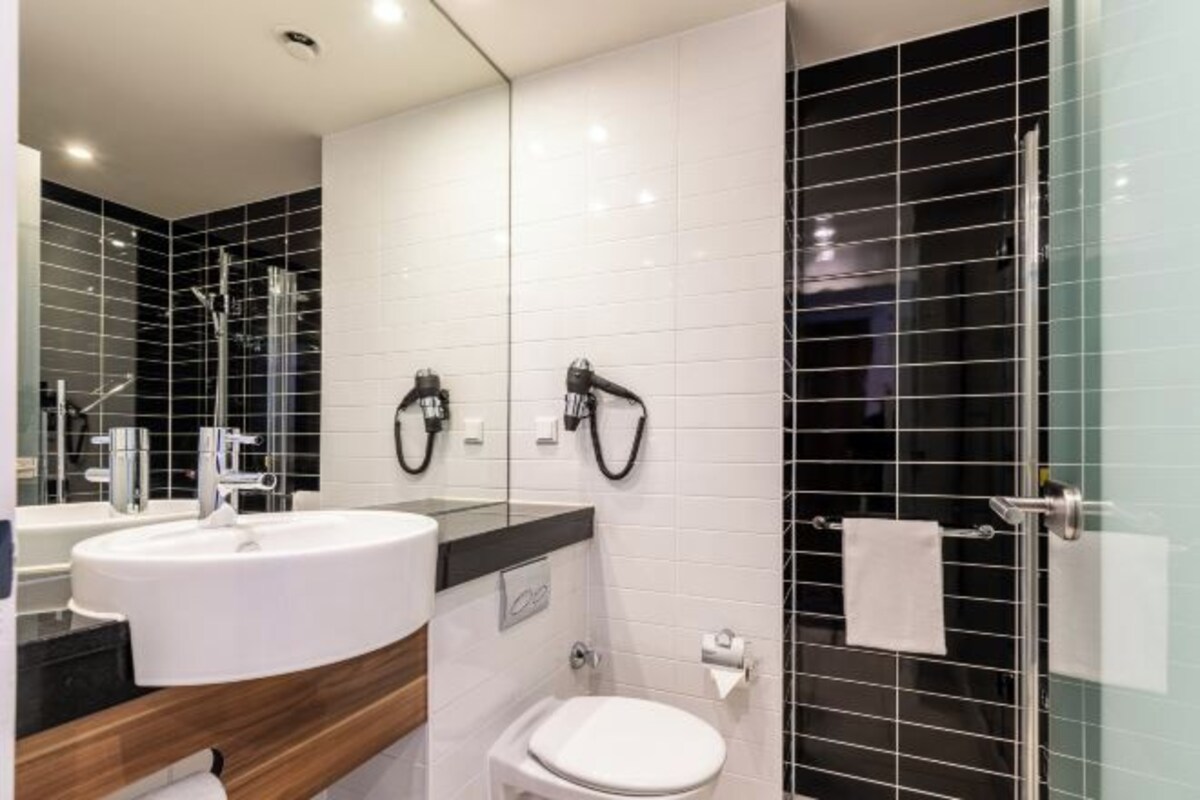 A modern bathroom with a white sink, a toilet, and a glass shower enclosure.