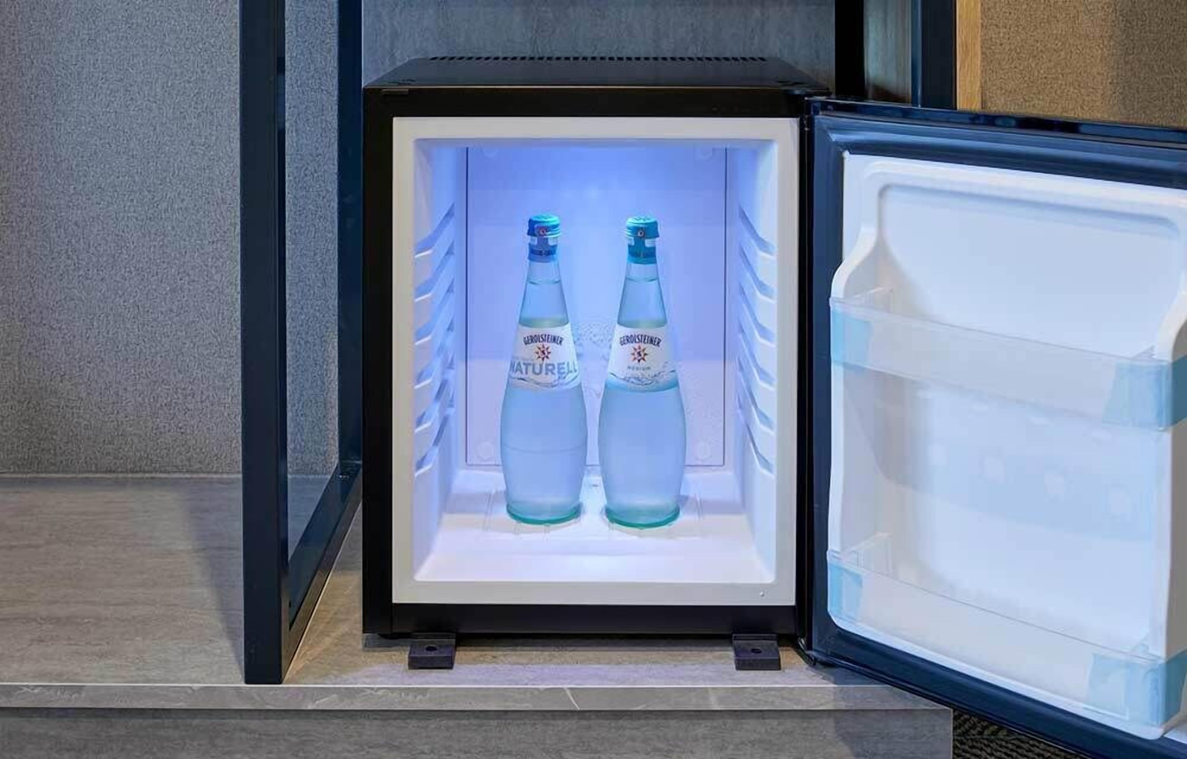 Un mini-réfrigérateur contenant deux bouteilles d’eau minérale Gerolsteiner Naturel.