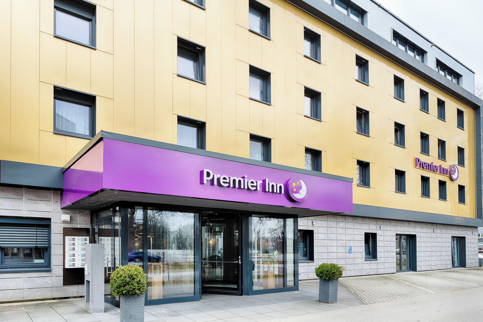 A Premier Inn hotel with a yellow facade, large windows, and a purple entrance.