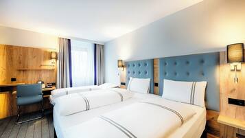A hotel room with a large bed, a desk, and a chair.