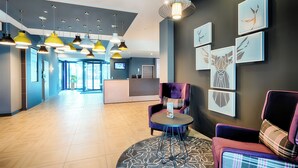A modern lobby with a reception desk, multiple seating areas, and artwork on the walls. - Premier Inn Lindau (Lindau)