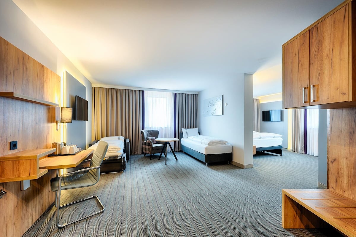 A hotel room with a bed, desk, chair, and a small table.
