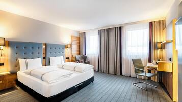 Ein Hotelzimmer mit einem großen Bett, einem Schreibtisch, einem Stuhl und einem Kleiderschrank.