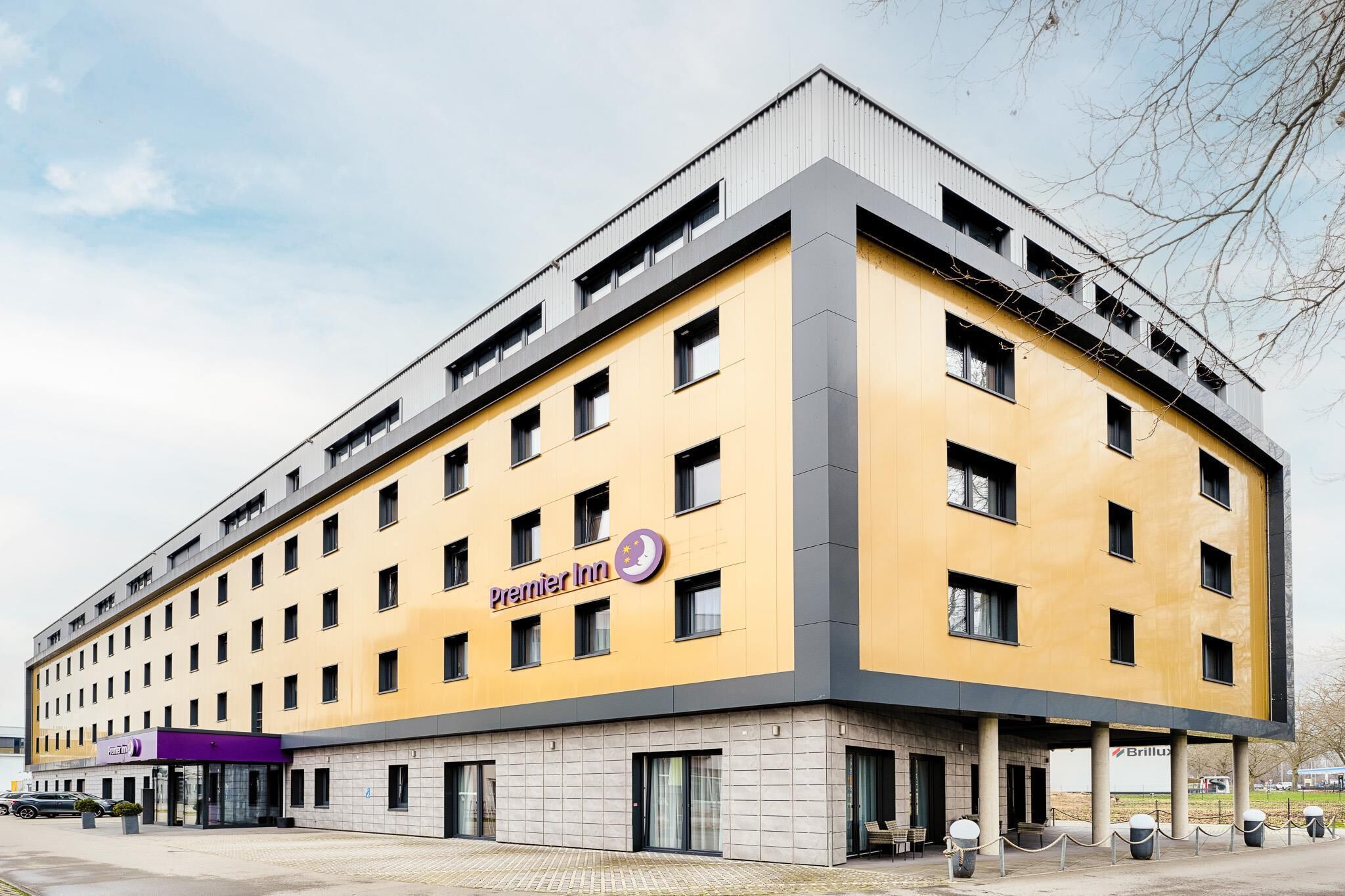 A modern hotel building with a yellow facade, multiple windows, and a prominent Premier Inn logo.