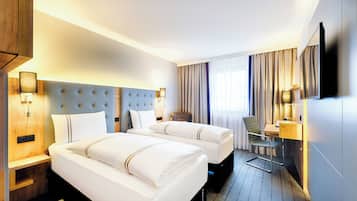 Habitación de hotel con dos camas, un escritorio, una silla, un televisor y una ventana con cortinas.
