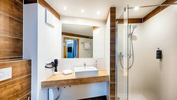 A modern bathroom with a glass shower enclosure, a white sink, and a wooden vanity.