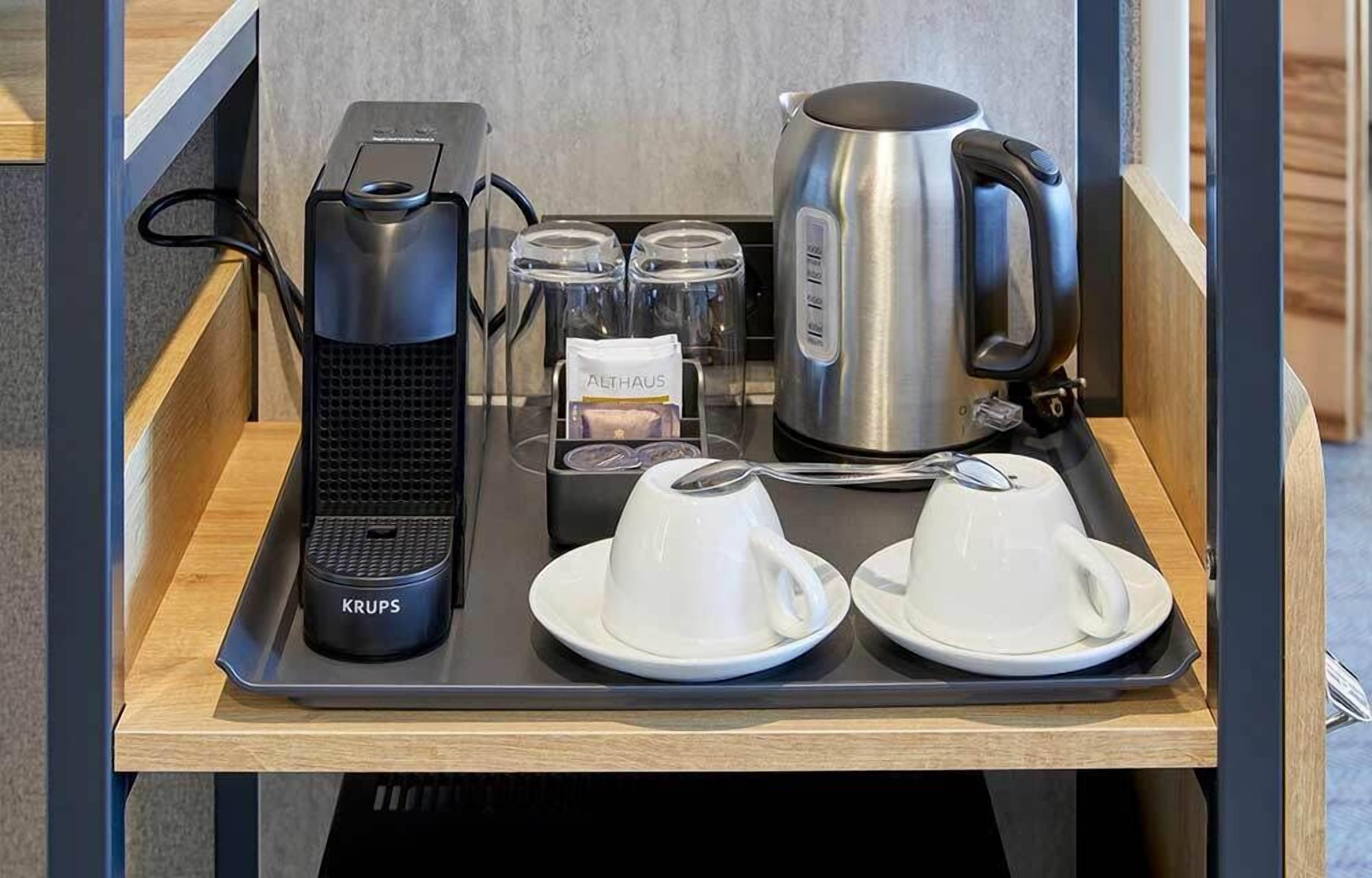 A tray with a coffee maker, a kettle, two cups, and a Krups coffee grinder.
