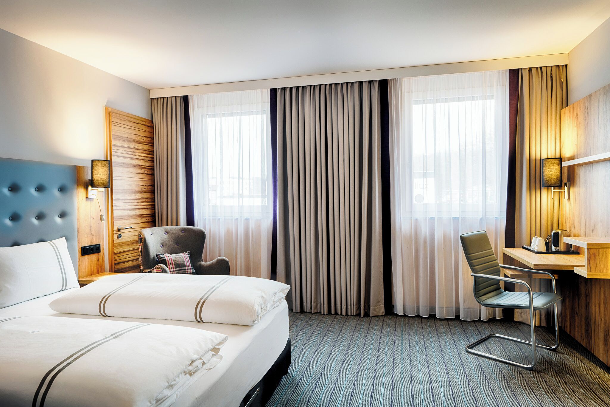 Une chambre d’hôtel avec un grand lit, un bureau, une chaise et une armoire.