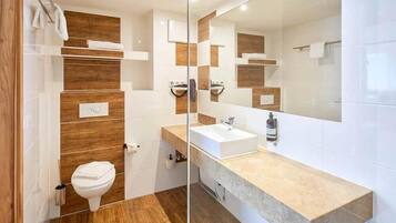 A modern bathroom with a wooden accent wall, a white sink, and a large mirror.