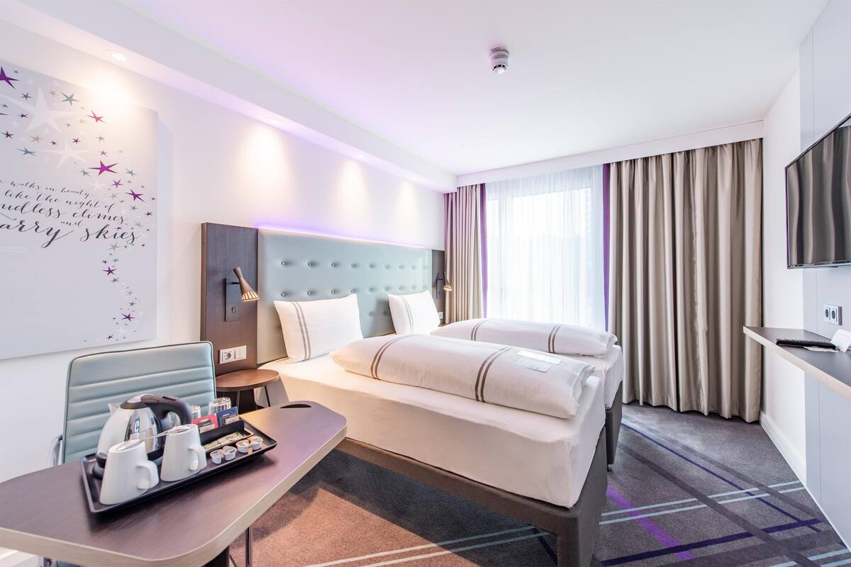 Una habitación de hotel con cama, mesita de noche y televisor montado en la pared.
