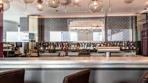 Een bar met een gepolijst bargedeelte, diverse alcoholische dranken en een grote spiegel erboven.
