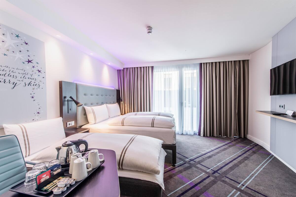 Habitación de hotel con cama, escritorio y bandeja de desayuno, televisión y pared con diseño de estrellas.