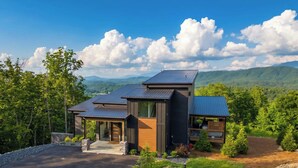 A modern house with a driveway, a covered porch, and a view of mountains. - Incredible Mountain Views | Indoor Pool | Luxury (Sevierville)