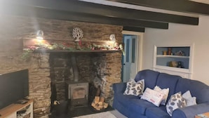 Un salon chaleureux avec une cheminée en pierre, un canapé bleu et un téléviseur.