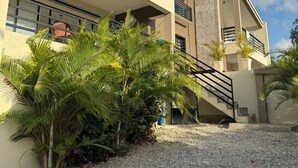 A modern building with multiple balconies, a staircase, and a gravel driveway. - Casa Vista Mar 1 (Rio San Juan)