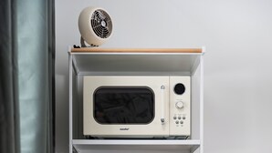 A compact kitchenette with a microwave, coffee maker, and a small refrigerator. - The Windmoor Lodge (Grayling)