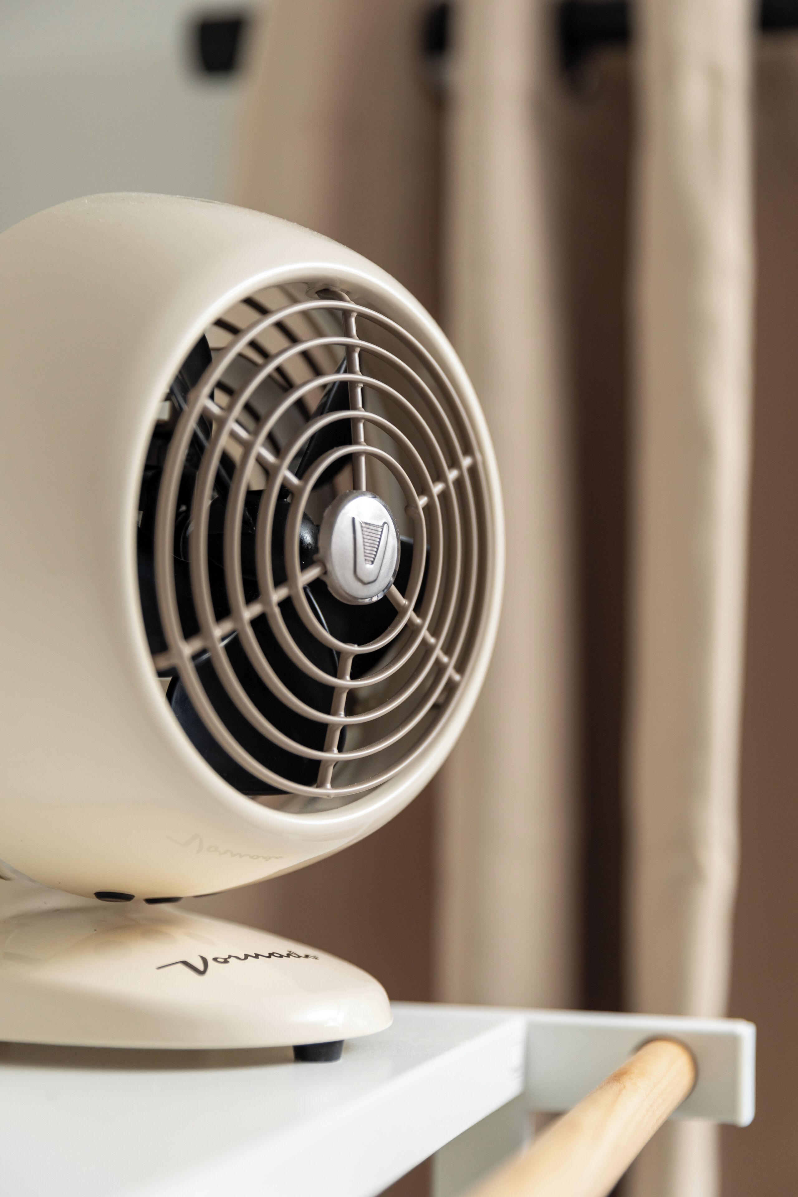 A white portable heater with a logo on the front, placed on a white surface.
