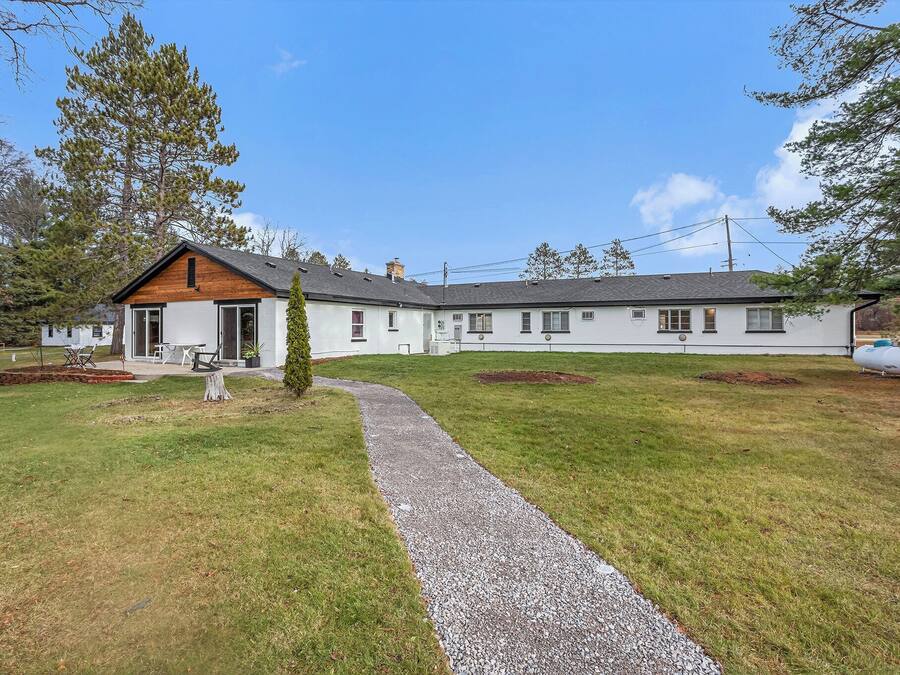 A two-story house with a gravel driveway leading to a wooden deck.
