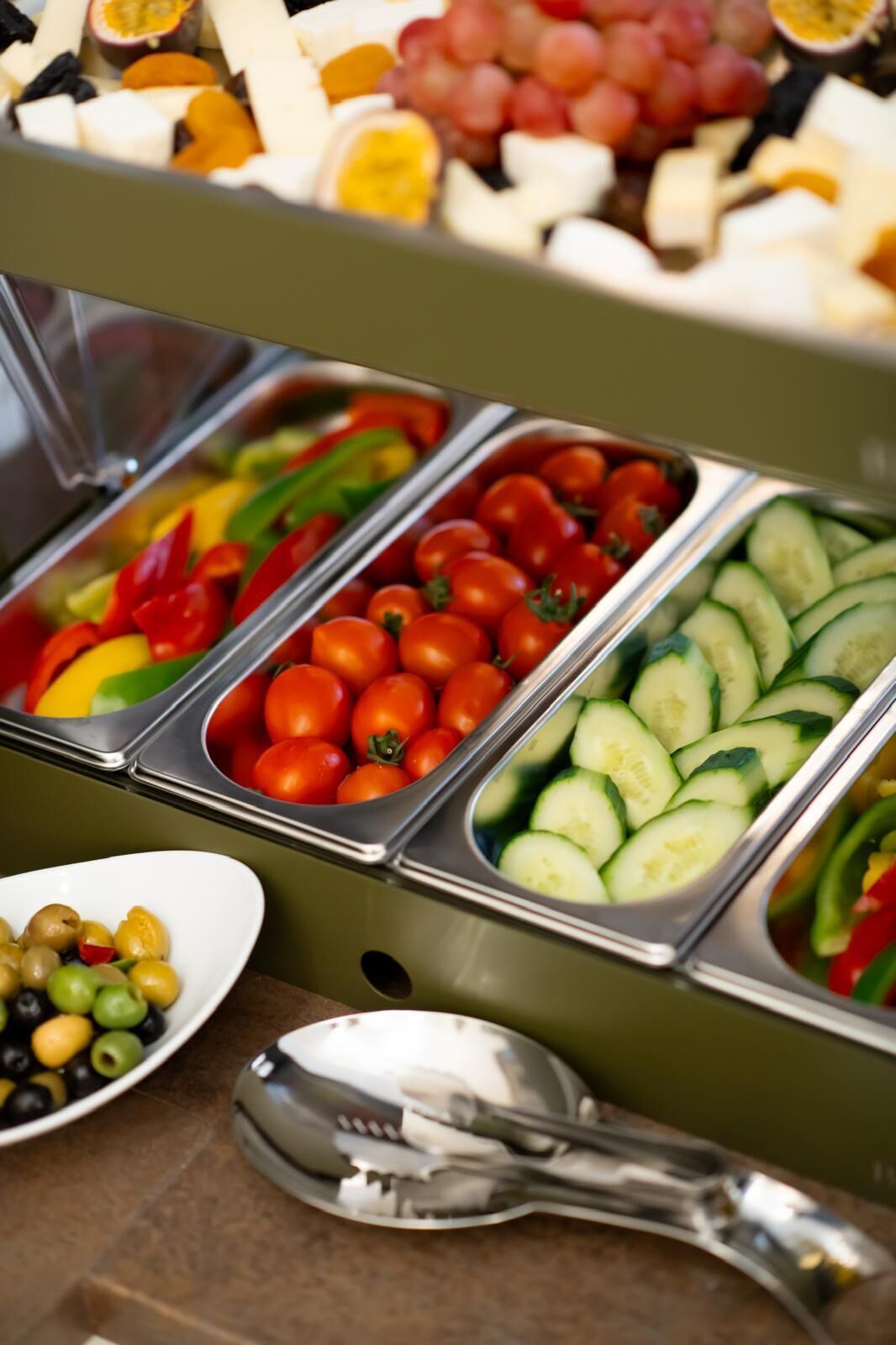 A buffet with various food options including fruits, vegetables, and cheeses.