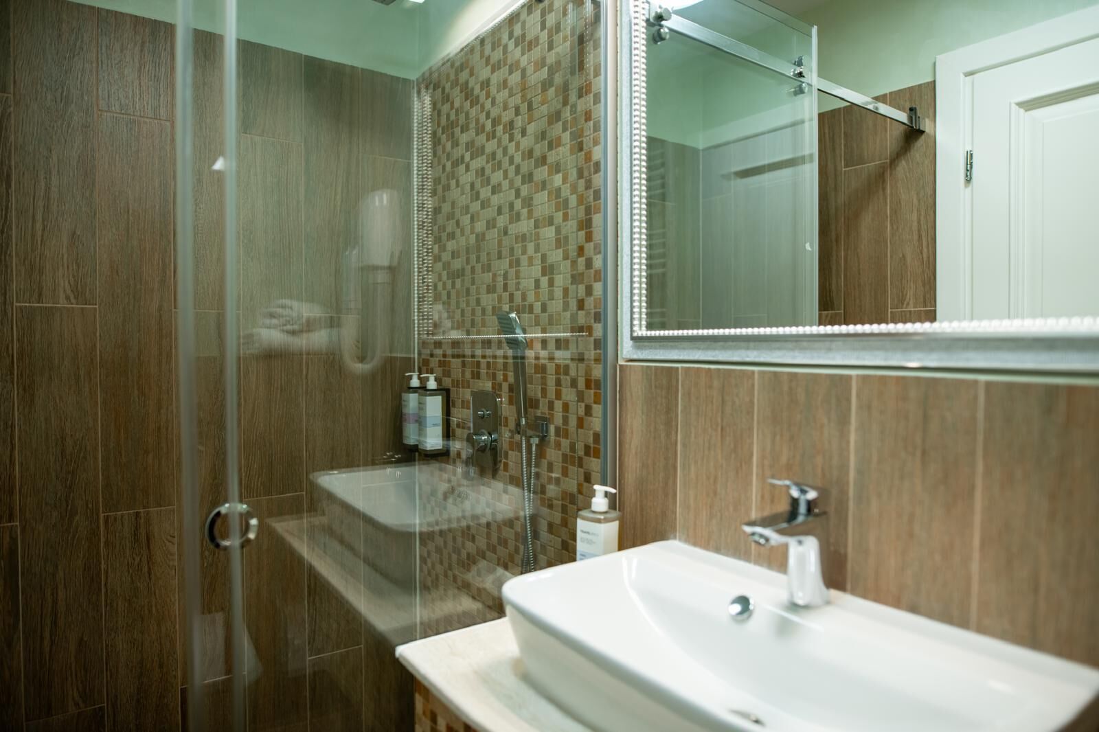 A modern bathroom with a glass-enclosed shower, a sink, and a mirror.