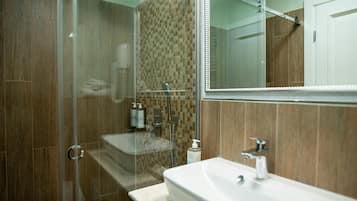 A modern bathroom with a glass-enclosed shower, a sink, and a mirror.