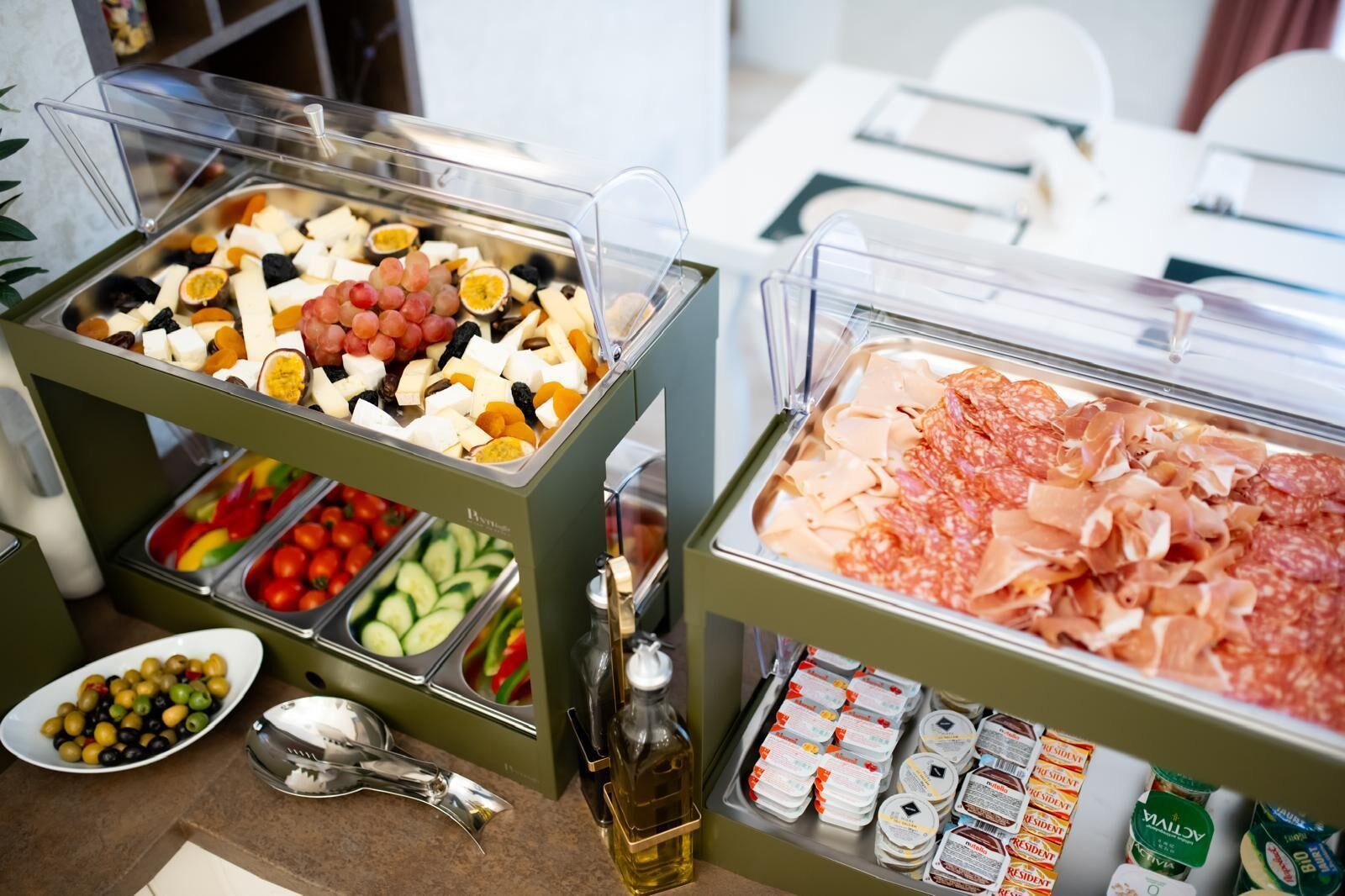 Buffet com diversas opções de comida, incluindo frutas, queijos, carnes e acompanhamentos.