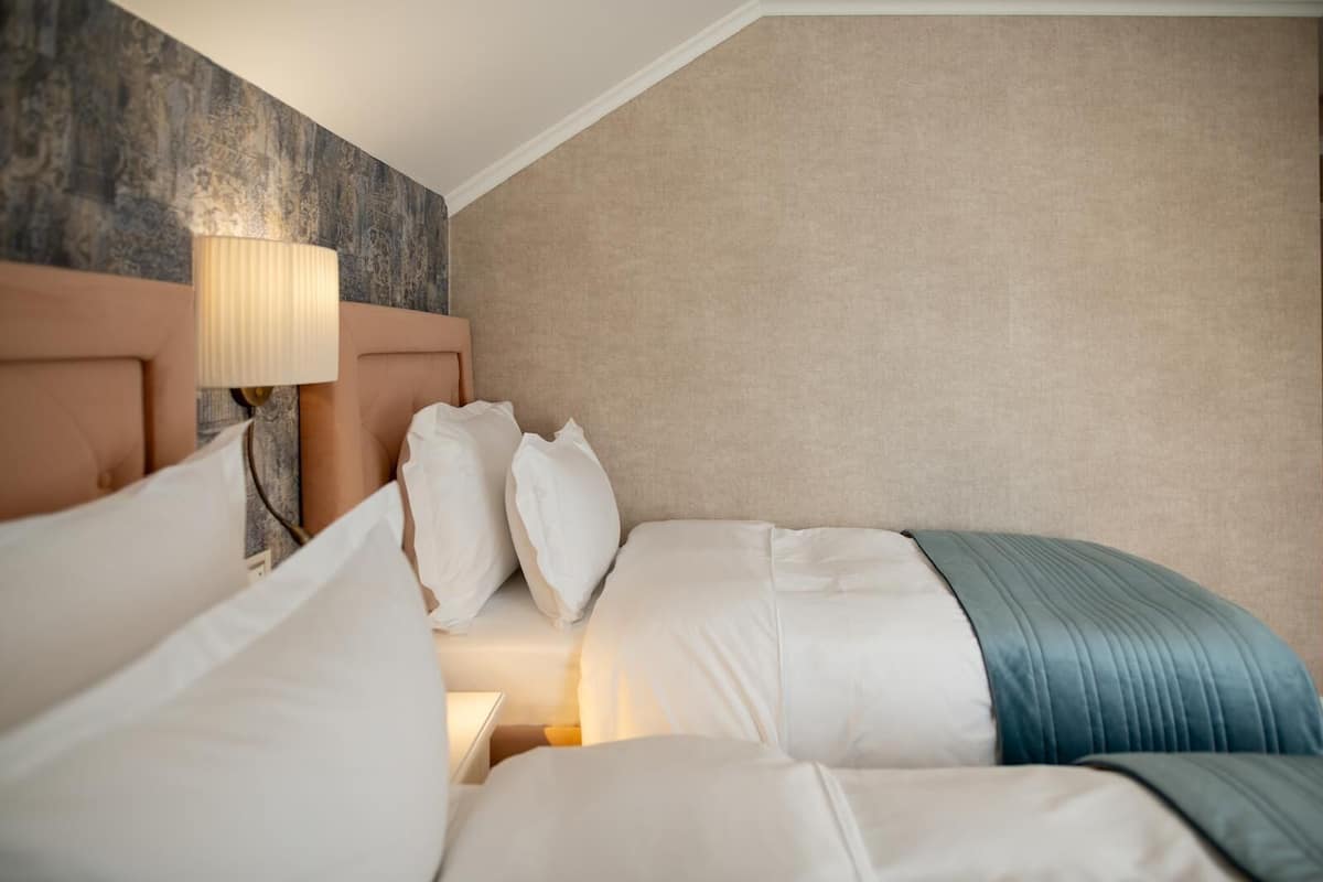 A hotel room with a large bed, a headboard with a lamp, and a textured wall behind the bed.