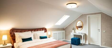A bedroom with a large bed, a desk, a mirror, and a skylight.