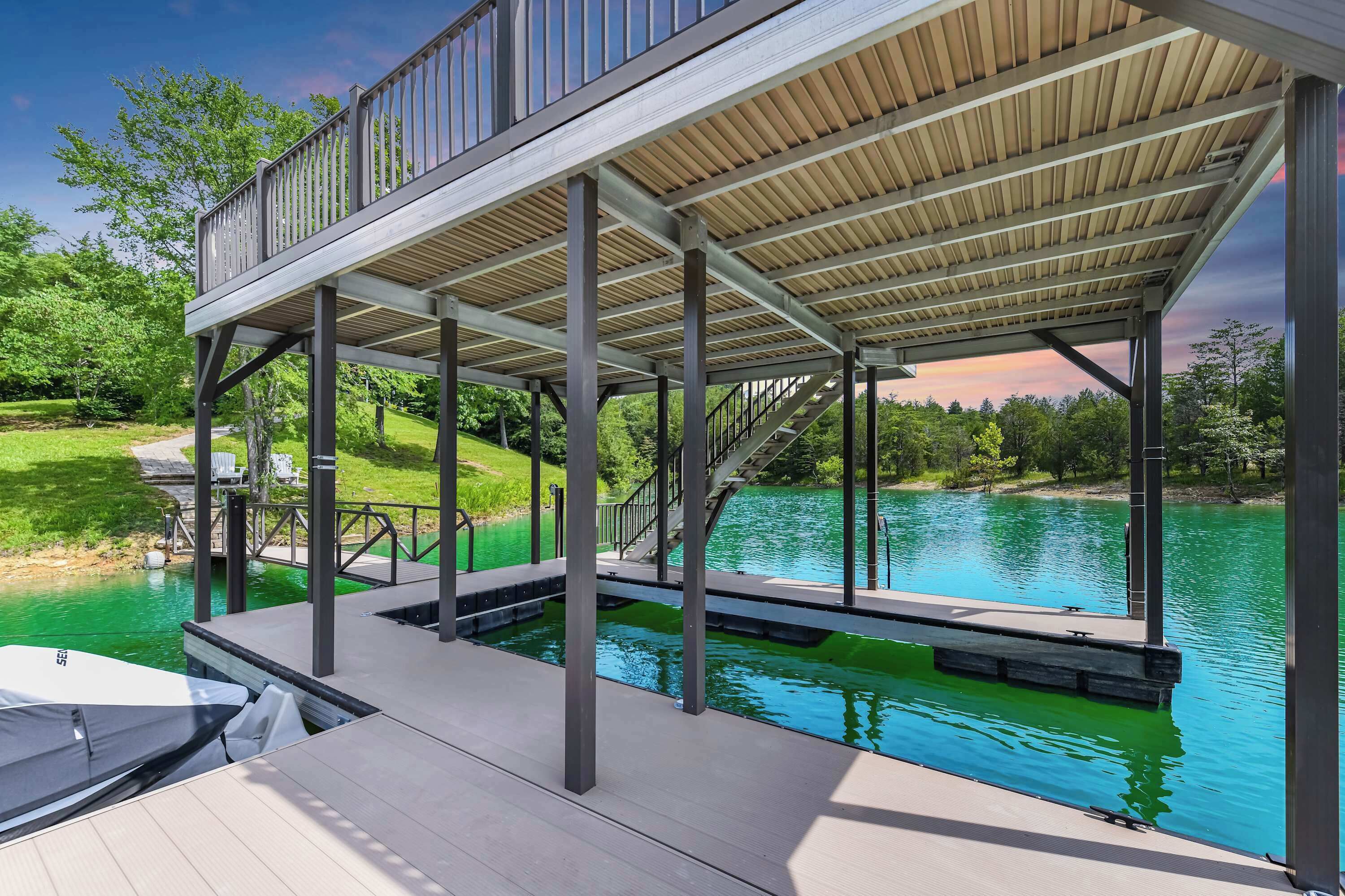 A covered dock with a staircase leading to a deck, overlooking a body of water.