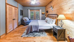Una camera da letto con un letto, un comodino, una ventola a soffitto e pareti in legno.