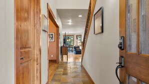 A hallway with wooden doors, a stone-tiled floor, and a staircase leading to a second floor. - Hot Tub Home Near Phil's Trail Sleeps 8 Pets OK (Bend)